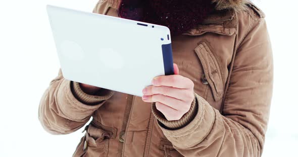 Smiling woman in fur jacket using digital tablet