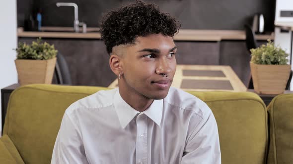 Portrait of Young Mixed Race Millennial Guy Sitting on Cozy Couch Well Dressed Male Smiling