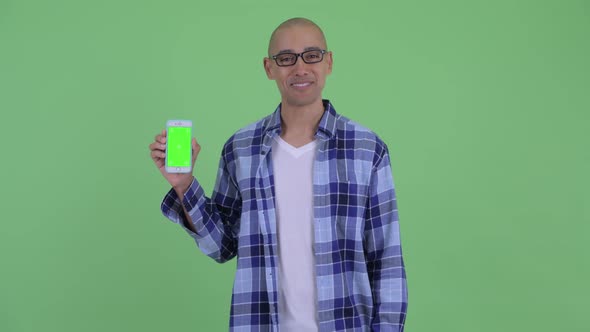 Happy Bald Hipster Man Showing Phone and Giving Thumbs Up