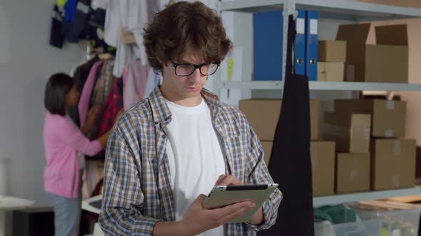 Portrait of Young Male Manager with Tablet Pc in Clothes Warehouse