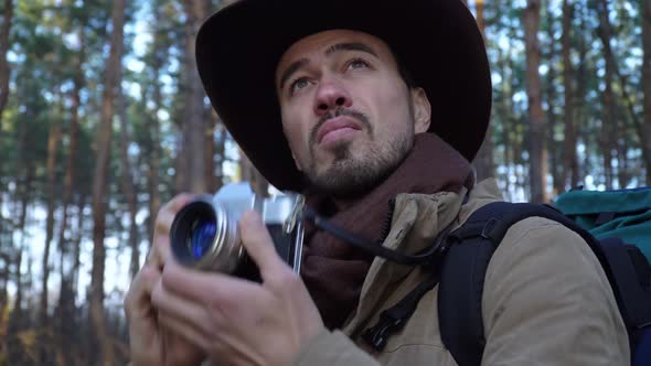 A Man in a Hat Takes Pictures in the Forest