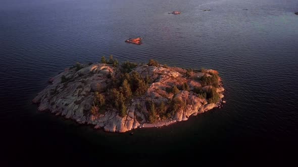 White Rock Island with Pine Trees in Big Blue Lake, Drone Aerial Wide Tilt Down to Overhead. Flying