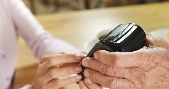 Senior woman paying the cafe bill through credit card terminal 4k