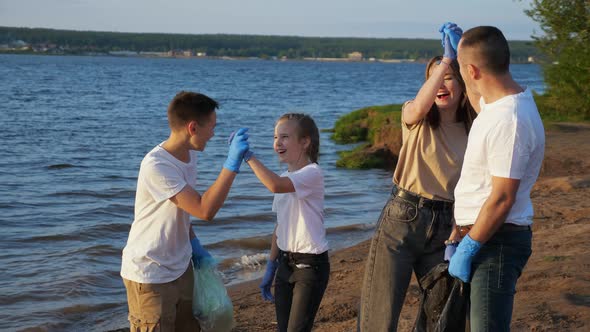 Family of Four with Teenagers Clearing the Beach From Plastic Debris