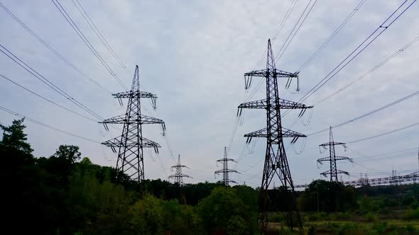 Electricity pylons bearing the power supply across a rural landscape during sunset. Selective focus.