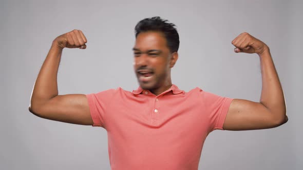 Indian Man Showing Biceps Over Grey Background