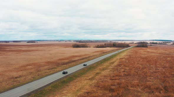 Cinematic Bird'seye View a Car Drives Over Rough Terrain on a Yellow Field