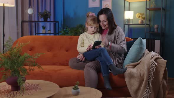 Mother and Girl Kid Daughter Looking on Smartphone Rejoicing Win Receiving Message with Good News