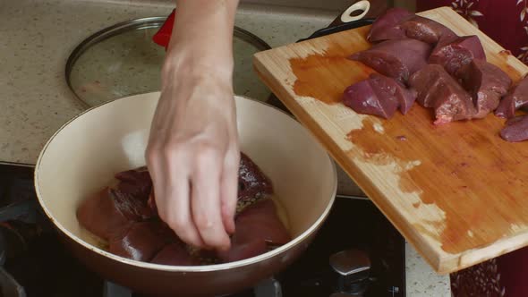 A Housewife Woman in a Home Kitchen Fries Fresh Pork Liver in a Frying Pan