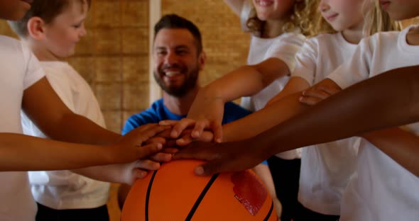 Basketball coach and schoolkids forming hand stack in the basketball court 4k