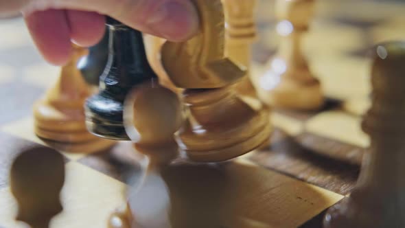 Capturing a knight by a bishop in a chess game. Man hand with a chess piece in a board game