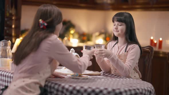 Smiling Girl Clinking Glass with Woman Drinking Organic Milk Sitting at Table with Ginger House on