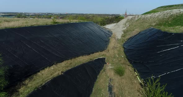 drone view of the sides of garbage dump hill covered with protective film.