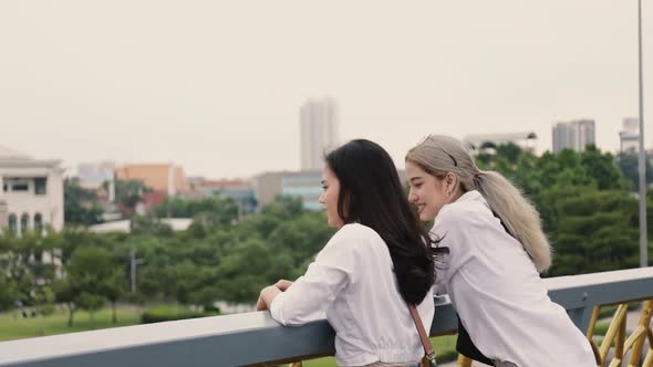 Asian lesbian couples enjoying traveling and talk while standing on the bridge.