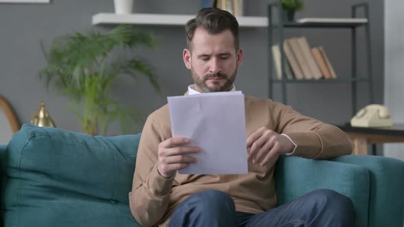 Man Reading Documents on Sofa