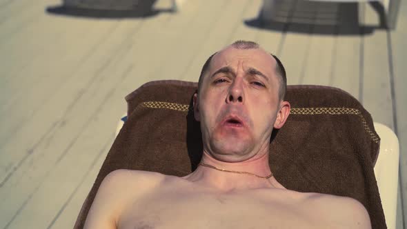 Closeup Portrait Bald Italian Man is Lying on the Beach on Sun Lounger Sunbathing