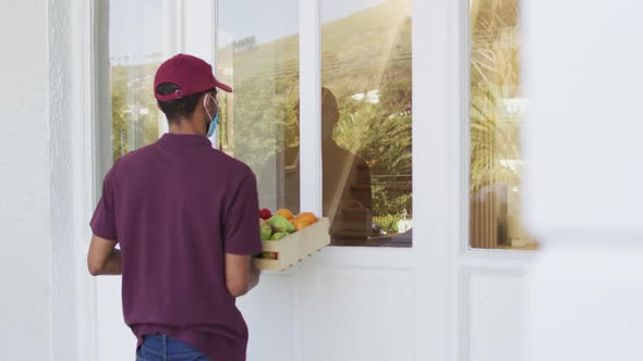 Delivery man delivering groceries to senior woman wearing face mask at home