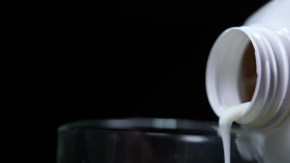 Closeup Fresh Organic White Milk Pouring in Slow Motion From Bottle in Glass