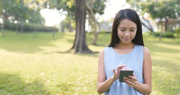 Woman looking at smart phone in the park 