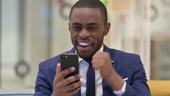 Portrait of African Businessman Celebrating Success on Smartphone 