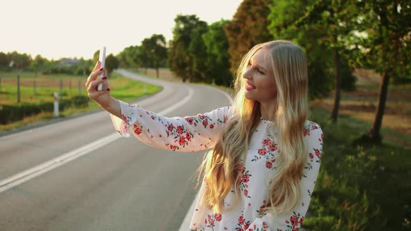 Woman Making Video Call Near Countryside Road. Young Lady Smiling and Using Modern Smartphone To