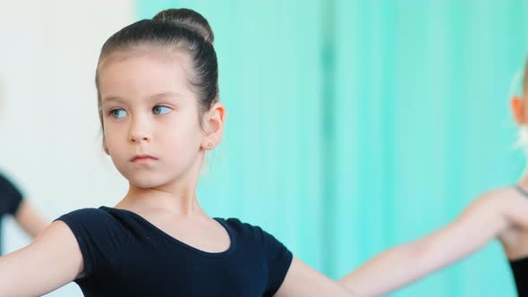 Concentrated Little Girl with Blue Eyes Practices Ballet