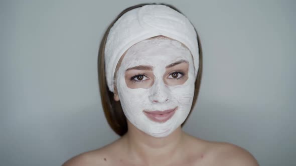 Portrait of Cute Girl with Cosmetic Mask on Face Looks with Smile Into Camera