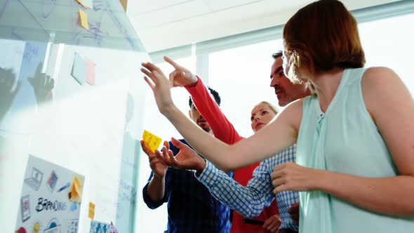 Team of business executives discussing over glass board