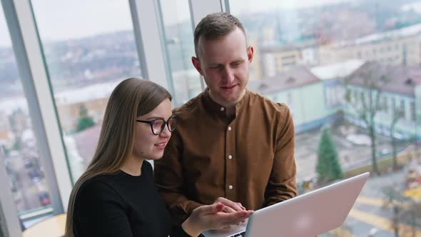 Young web designers look at laptop and discuss. Teamwork, coworking concepts.