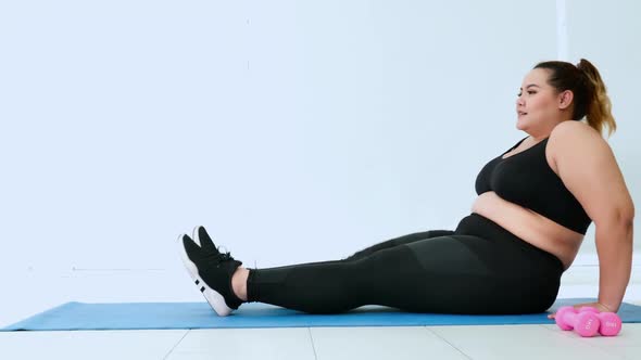 Overweight young woman in sportswear exercising to lose weight at home