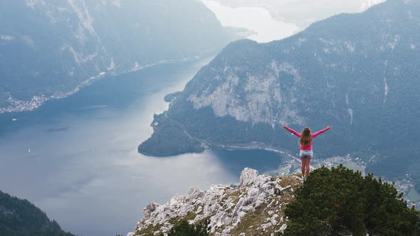Back View of Young Woman Rise Her Hands Enjoying Amazing View of Lake in Mountains
