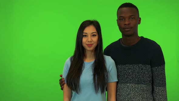 A Young Asian Woman and a Young Black Man Point at the Camera and Nod - Green Screen Studio