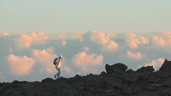 Female Hiking Alone Edge of High Mountain with Cinematic Pink Clouds View