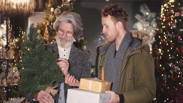 Senior and Young Man Looking at Christmas Tree Shopping at Christmas Decorations Store