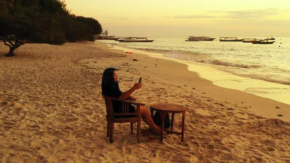 Single female happy and smiling on tranquil shore beach time by blue water and bright sand backgroun