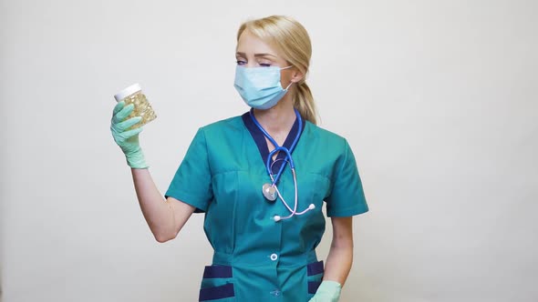 Medical Doctor Nurse Woman Wearing Protective Mask and Rubber or Latex Gloves - Holding Pills