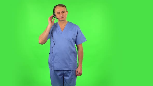 Medical Man Talking on Headphones at Support Service. Green Screen