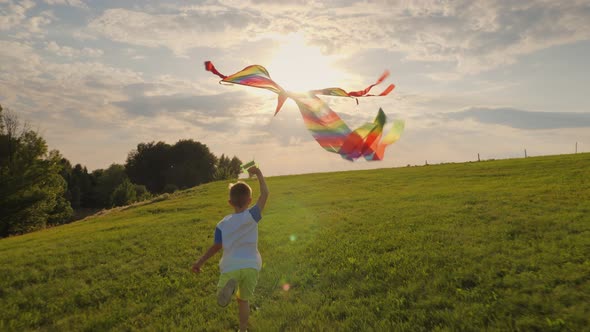 Little Boy Running Playing with a Kite in the Meadow at Sunset