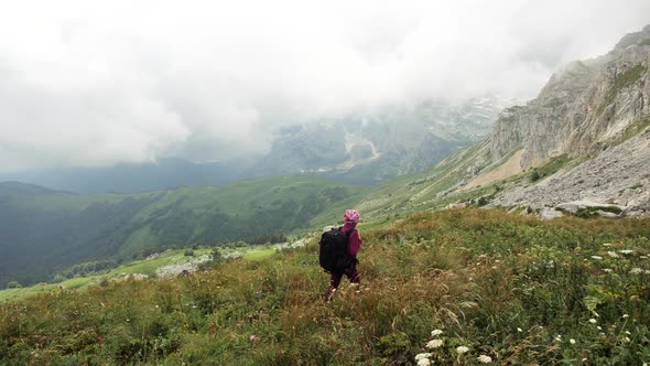 Young Woman with Backpack Walks Towards the Summit. Slow Motion. Lady Is Hiking in Beautiful