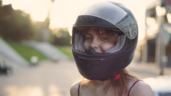 Portrait of Beautiful Young Redhaired Woman Motorcyclist in Helmet at Sunset