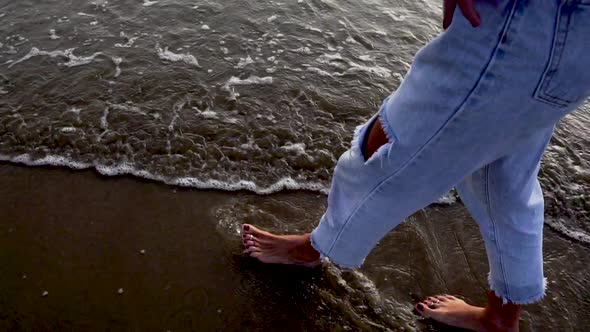 Close up of of woman's Caucasian feet walking on bathing shoreline. Slow motion