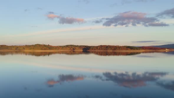 Drone aerial view of a lake reservoir of a dam with perfect reflection on the water of the sunset in