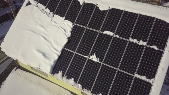 Closeup surface on a house roof covered with solar panels in winter with snow on top.