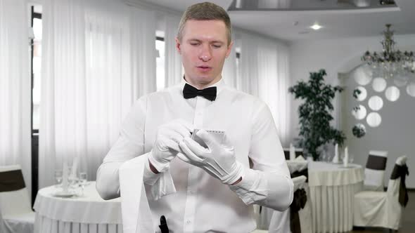 Waiter in a White Shirt and Bowtie Writing Down an Order in a Cafe