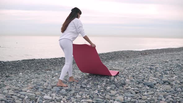 Woman Is Lying Sportive Yoga Mat on Pebble Beach To Practicing in Daytime