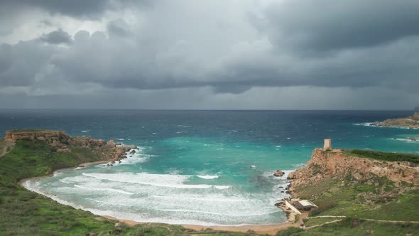 AERIAL: Black Clouds Surrounds Ghajn Tuffieha Beach on a Gloomy Winter Day