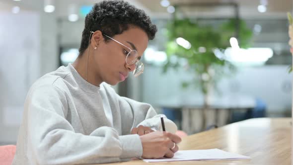 Young Casual African Woman Writing on Paper 