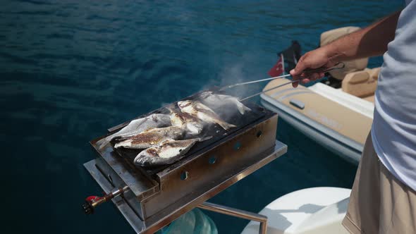 Closeup of Preparing Grilled Sea Bass Fish Outdoors in the Open Sea While Traveling By Boat Slow