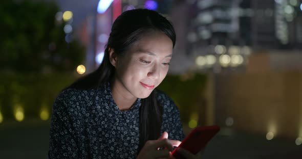 Woman use of smart phone in city at night