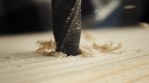Close up static video of drilling on wood plate. Shot with RED helium camera in 8K